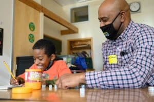 A happy child works on math with a volunteer tutor.