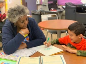 A volunteer math tutor provides critical support to an eager child.