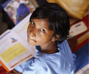 Indian Girl looking up, book in lap - UNESCO International Literacy Day