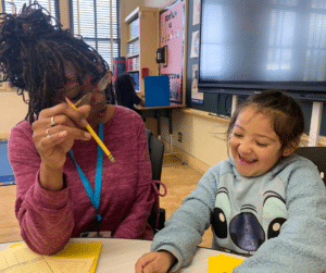 A tutor puts the smile of learning on the faces of eager young children.